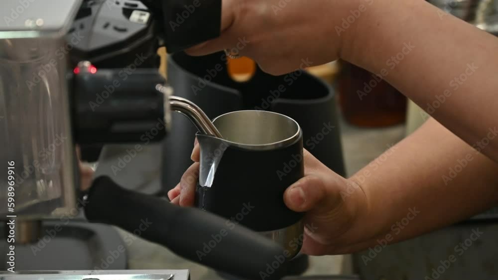 Barista using espresso machine for steaming milk. A milk steamer is a device used to heat milk and is commonly found attached to espresso machines. Barista using espresso machine for steaming milk. A milk steamer is a device used to heat milk and is commonly found attached to espresso machines.