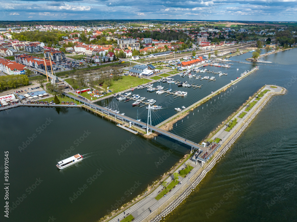 Marina in Gizycko, Poland, Niegocin lake - drone aerial photo of sailboats and bridges, blue cloudy sky, city in the background