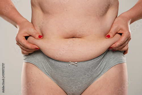 Woman pinching her fat belly, close up.