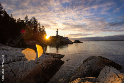 Sunrise over a tall lighthouse situated on a rugged rocky coast - Point Atkinson Lighthouse Park, Vancouver  photo