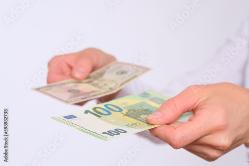 Female hands hold one hundred euro banknote and a banknote of american dollars