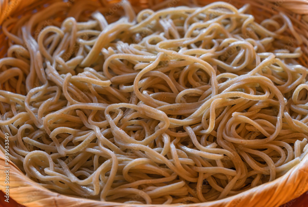 Close-up on a traditional Japanese basic chilled soba noodles made from buckwheat and served in the mori soba style in a bamboo weave flat basket called zaru soba. Close-up on a traditional Japanese basic chilled soba noodles made from buckwheat and served in the mori soba style in a bamboo weave flat basket called zaru soba.