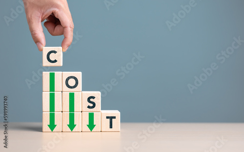 Lean or Cost reduction concept. Optimize manufacturing management. Decreasing company expense to maximize profits. Hand puts wooden cube with words cost and green down arrows. Business improvement. photo