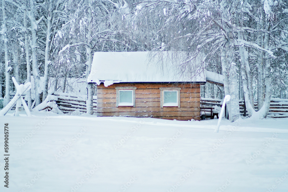 Rustic wooden cabin in the snowy forest. Wooden cottage or house with a wooden fence. Deciduous forest with snow covered birch trees. Rural living in Lapland, Finland. Rustic wooden cabin in the snowy forest. Wooden cottage or house with a wooden fence. Deciduous forest with snow covered birch trees. Rural living in Lapland, Finland.