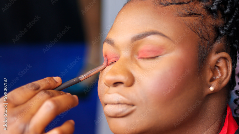Close up of a woman applying red blush on eye brow.	