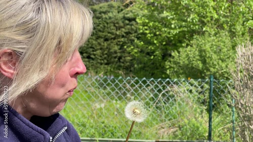 Frau pustet eine Pusteblume im Garten photo