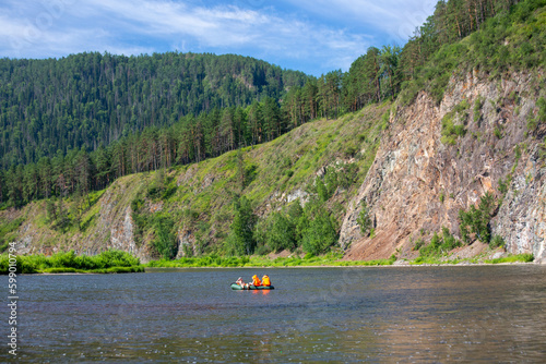 Tourists on boats float down the river in the wilderness in summer. Tourism, active recreation.