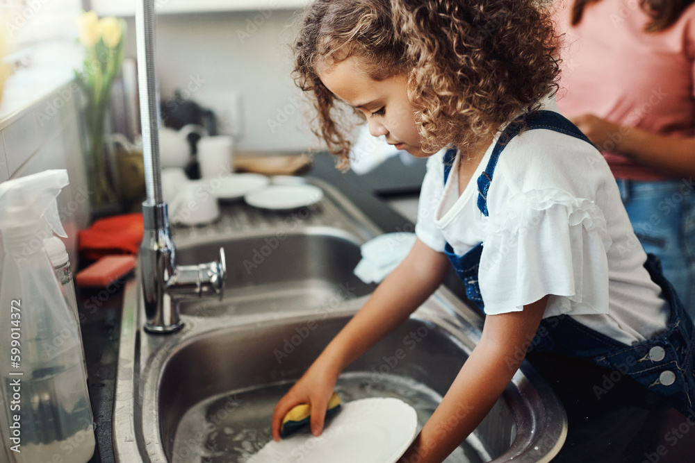 Moms got me doing the dishes. an adorable young girl standing and washing the dishes in the kitchen sink at home. Moms got me doing the dishes. an adorable young girl standing and washing the dishes in the kitchen sink at home.