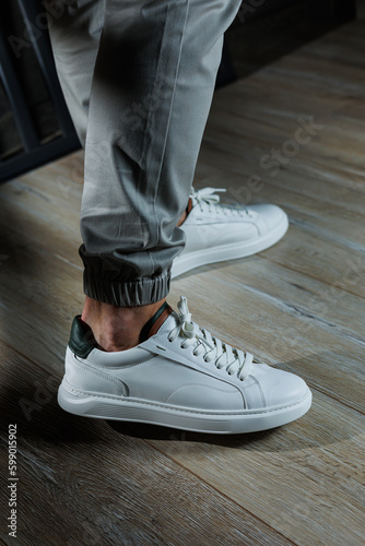 Men's summer shoes. Close-up of male legs in white leather sneakers. Collection of men's leather shoes