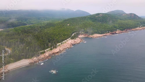 4K Aerial Drone Orbit Arc through Clouds over Pine Tree Peninsula. Water, Trees, Rocks, Coast visible