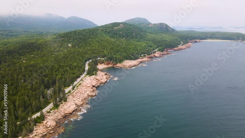 4K Aerial Drone Orbit Arc through Clouds over Pine Tree Peninsula. Water, Trees, Rocks, Coast visible