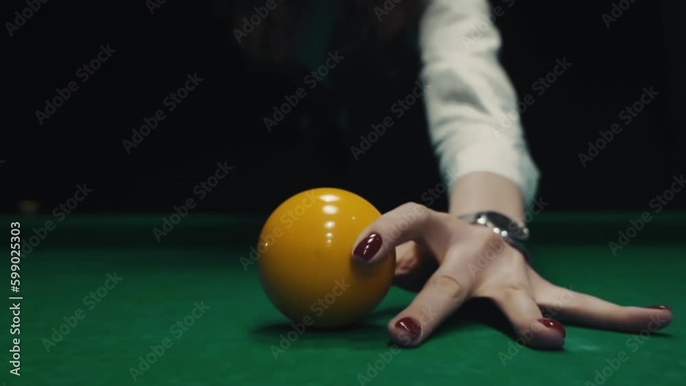 The girl puts a yellow billiard ball in the center. Woman playing snooker on green color table