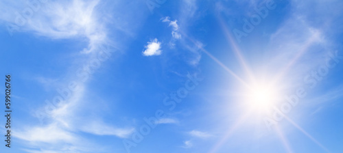 There are light clouds and a bright sun in the blue sky. Wide photo.