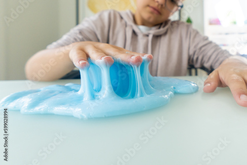 Closeup of young girl hands playing with blue sticky slime
