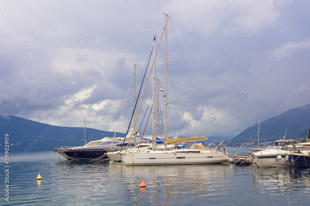 Sailboats on water, beautiful Mediterranean landscape. Montenegro, Adriatic Sea. View of Bay of Kotor near Tivat city on cloudy day