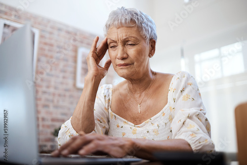 This was not part of the retirement package. a senior woman looking stressed while using a laptop at home.