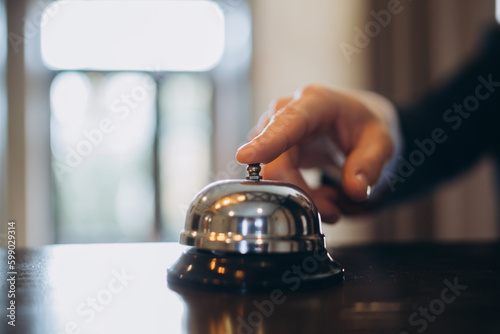 Arrival at the hotel. A man ringing a hotel reception service bell to attract attention.
