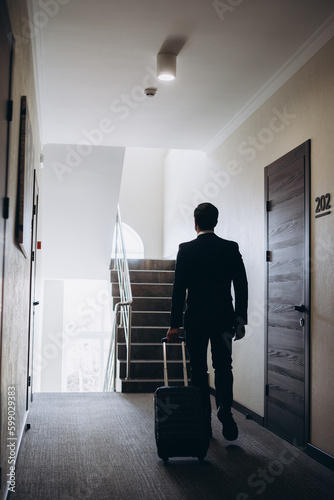 Businessman walking with luggage in a hotel corridor..