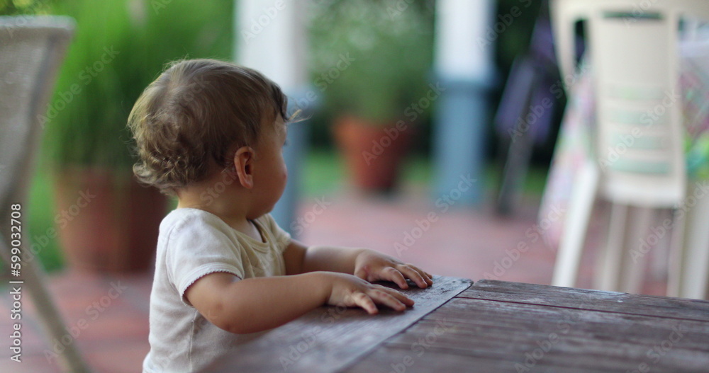 Toddler boy supporting himself into wooden furniture table Toddler boy supporting himself into wooden furniture table
