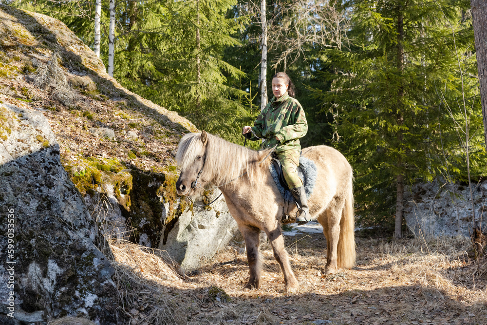 Icelandic horse and camouflaged woman in Finnish spring enviroment