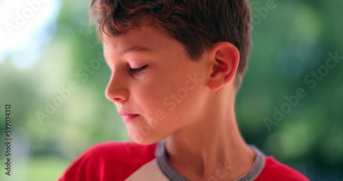 Thoughtful young boy child thinking while taking a bite of sandwich