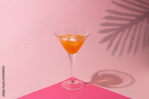 Martini cocktail with a lot of ice on a pink background, with a shadow of palm leaves, minimalist, summer concept