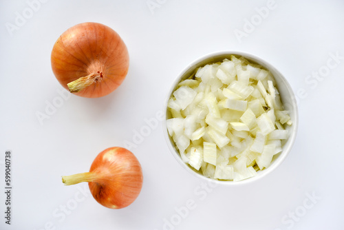 Two onions and chopped onion on a white plate. Onion on a white background.