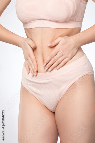Girl pulls the skin on the abdomen, showing the body fat. Treatment and disposal of excess weight, the deposition of subcutaneous fat. © Dimid