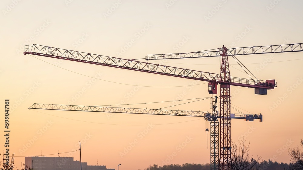 Construction site on the evening sky. Building site with three hoisting, cranes on red sky background