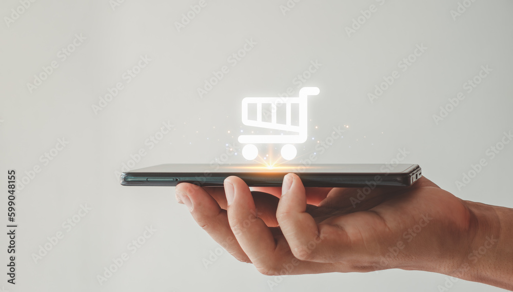 Online shopping icon on smart phone for global concept. The person's hand is holding a smartphone with a shopping cart icon. e-commerce. - obrazy, fototapety, plakaty 