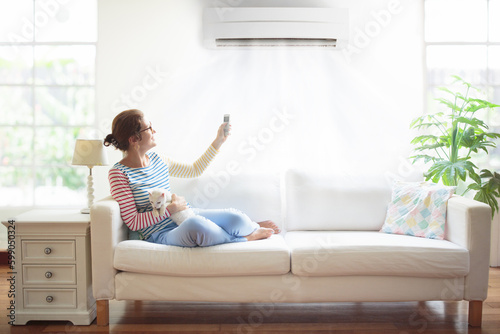 Woman with air conditioner remote control.