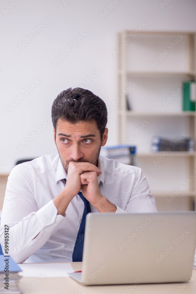 Young male employee and too much work in the office Young male employee and too much work in the office
