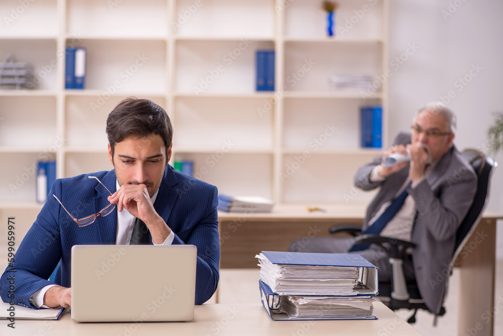 Old male boss and young male employee in the office Old male boss and young male employee in the office