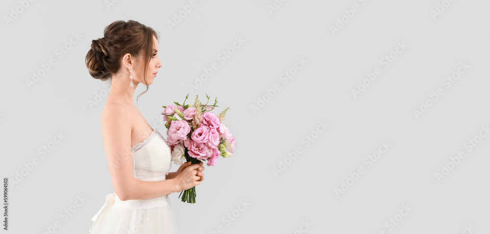 Portrait of beautiful young bride holding wedding bouquet on light background with space for text