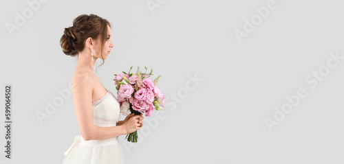 Fototapeta Naklejka Na Ścianę i Meble -  Portrait of beautiful young bride holding wedding bouquet on light background with space for text