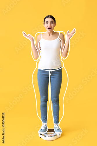 Surprised young woman after slimming standing on weight scales against yellow background