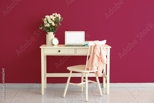 Fototapeta Naklejka Na Ścianę i Meble -  Modern workplace with laptop and daisy flowers in vase near pink wall