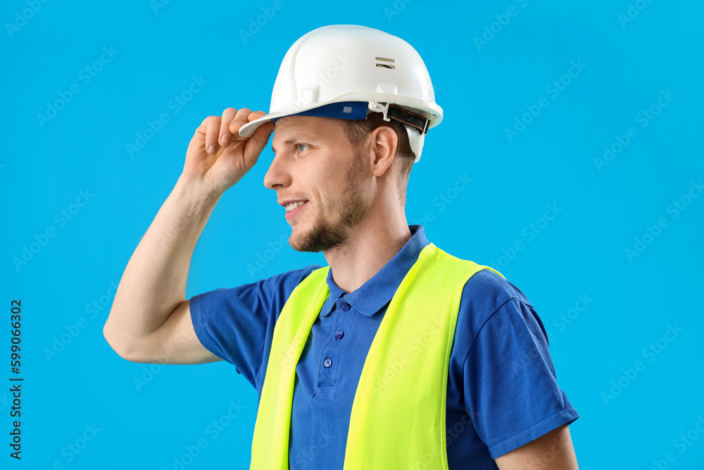 Male worker in vest and hardhat on blue background Male worker in vest and hardhat on blue background