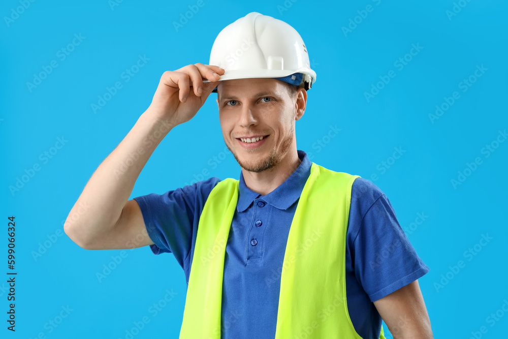 Male worker in vest and hardhat on blue background