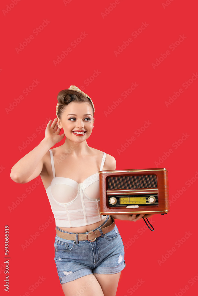 Young pin-up woman with retro radio receiver on red background