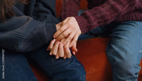 Fotografie Close-up of two lesbian women family couple, girls friends holding caressing hands together, showing love to each other at home room sitting on couch
