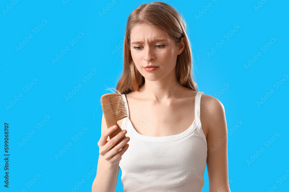 Upset young woman with comb and fallen down hair on blue background Upset young woman with comb and fallen down hair on blue background