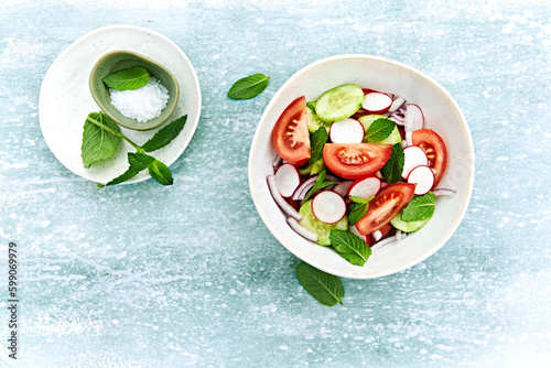 Spring tomato and cucumber salad with radishes and mint leaves