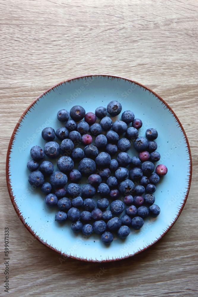 Turquoise plate with fresh blueberries on wooden background. Top view. Turquoise plate with fresh blueberries on wooden background. Top view.
