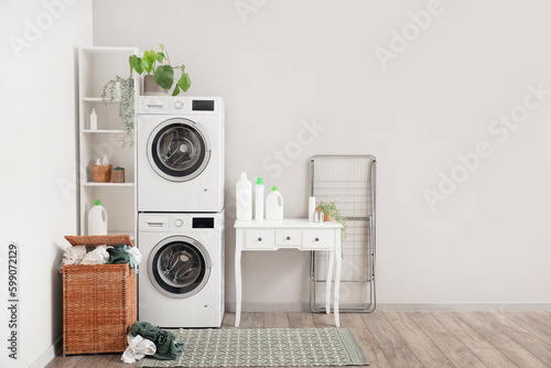Interior of laundry room with washing machines, table and basket