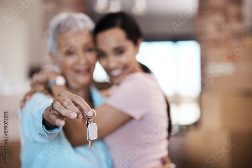 What makes a home are the memories made in it. a senior woman standing next to her daughter and holding up the keys to her new home.