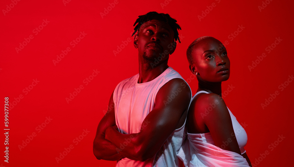 Obraz premium Stay determined. Red filtered shot of a sporty young man and woman posing together in the studio.