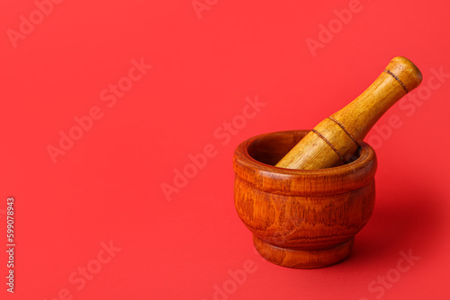 Wooden mortar and pestle on red background