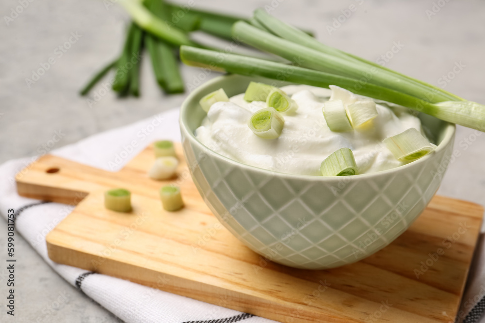 Bowl of tasty sour cream with green onion on table, closeup Bowl of tasty sour cream with green onion on table, closeup