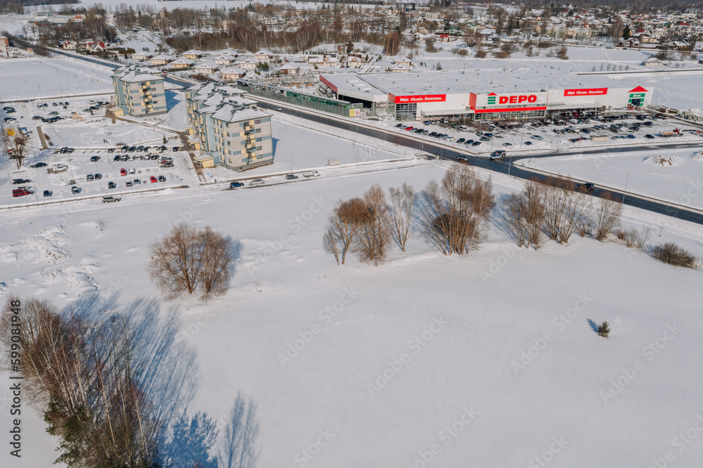Obraz premium An aerial view of a city during winter, surrounded by built structures and skiing pistes covered in snow from the high angle viewpoint